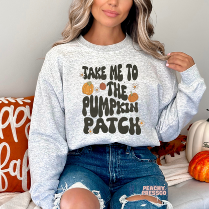 Woman wearing an ash grey crewneck sweatshirt featuring a retro pumpkin patch graphic with pumpkins and daisy accents.