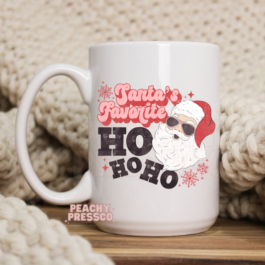 White mug featuring Santa Claus in sunglasses with pink text reading Santas Favorite HO HO HO.