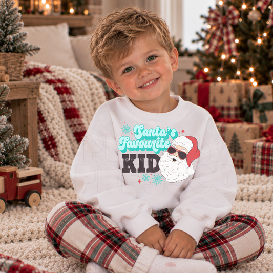 Boy wearing a white Santa’s Favourite Kid Christmas sweatshirt with a festive retro Santa design.