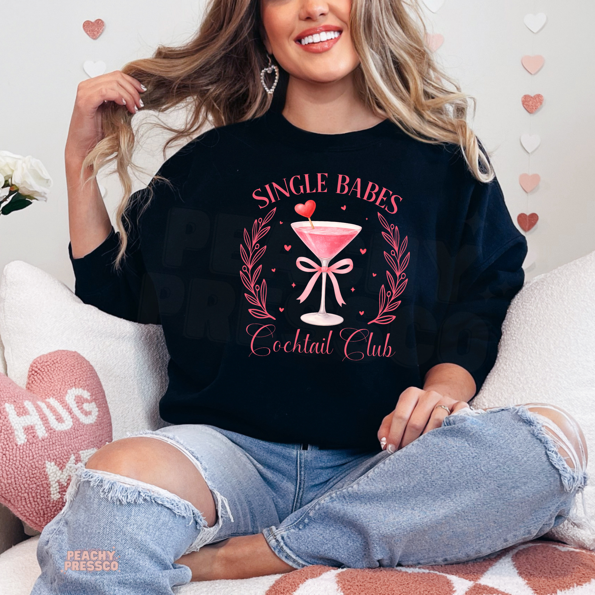 Black sweatshirt featuring a Single Babes Cocktail Club design with a pink martini glass, heart stirrer, ribbon bow, and playful Valentine's aesthetic.