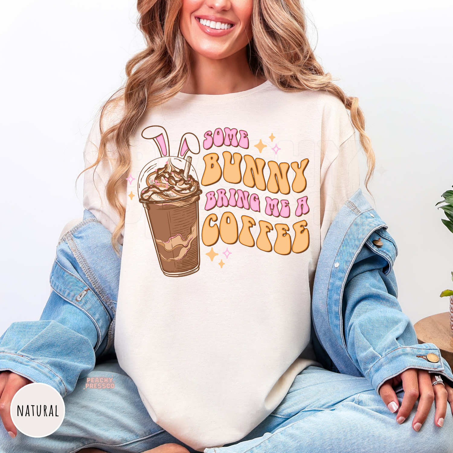 Natural shirt featuring a cute Some Bunny Bring Me A Coffee graphic with bunny ears and iced coffee.