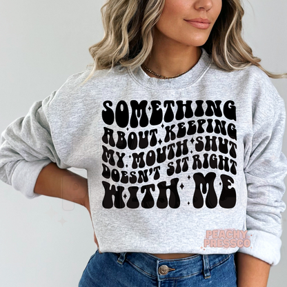 Ash grey crewneck sweatshirt with the humorous "Something About Keeping My Mouth Shut Doesn't Sit Right With Me" graphic in bold black retro typography.