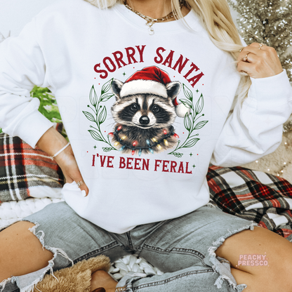 Women wearing a white crewneck sweatshirt with a funny Christmas raccoon wrapped in lights, styled with ripped denim jeans.