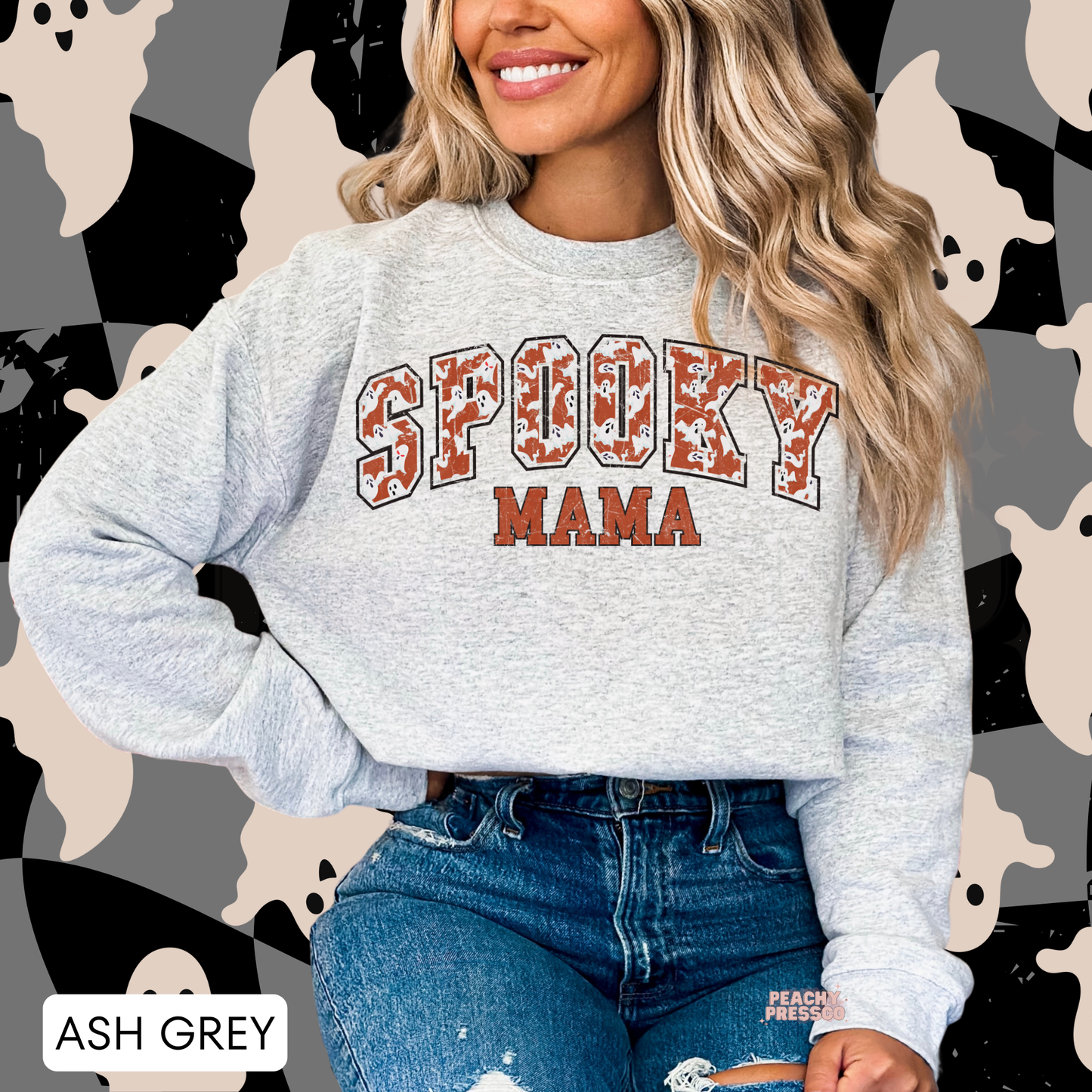 Woman wearing an ash grey Spooky Mama Halloween crewneck sweatshirt with distressed ghost varsity lettering.