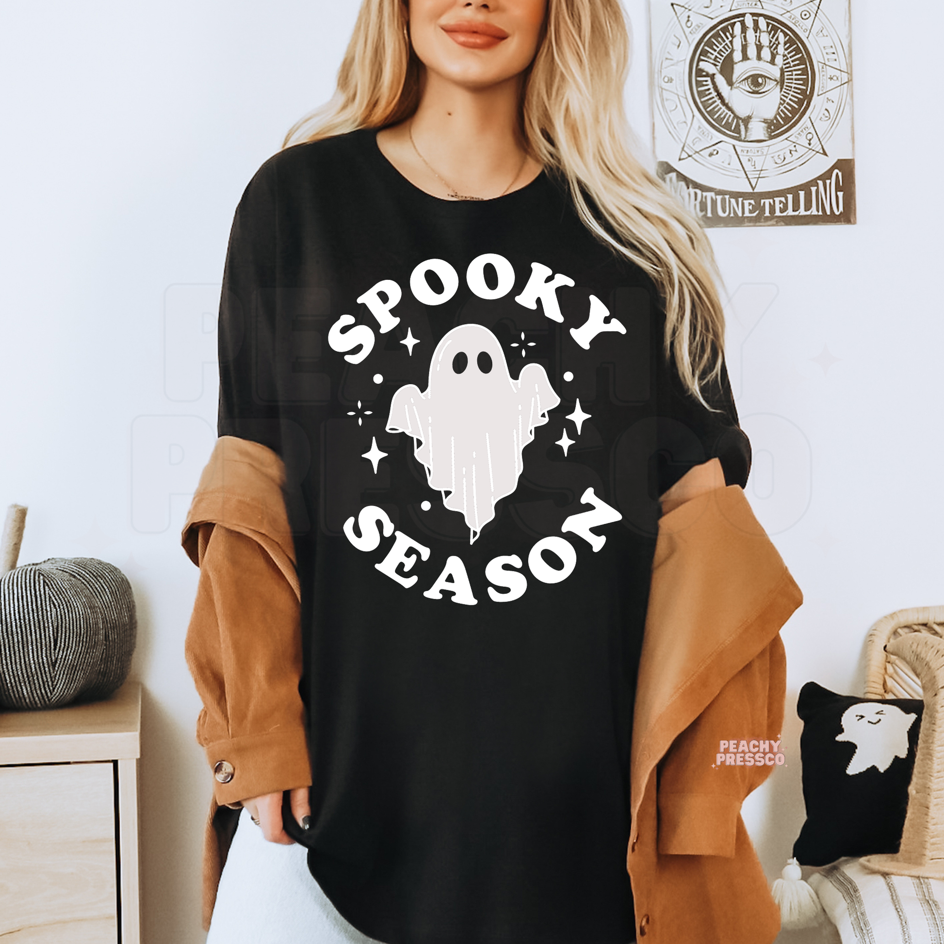 Woman wearing a black Spooky Season ghost Halloween t-shirt with a minimalist ghost graphic and sparkles.