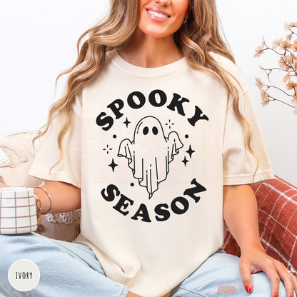 Woman wearing an ivory Comfort Colors Spooky Season ghost shirt with a simple black ghost Halloween design.