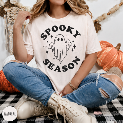 Woman wearing a natural colored Spooky Season ghost Halloween shirt with a minimalist ghost illustration.