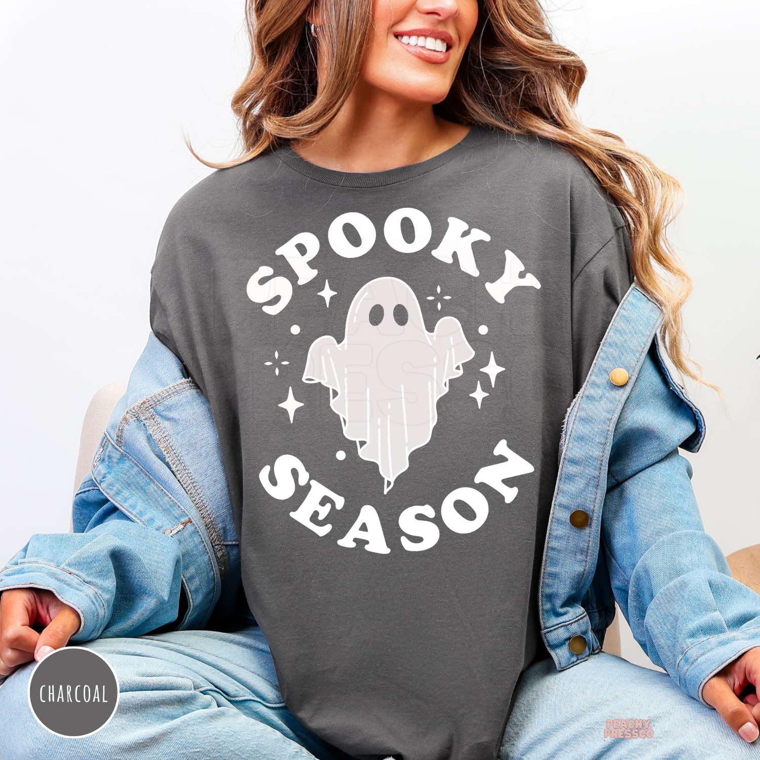 Woman wearing a charcoal gray Spooky Season ghost sweatshirt layered with a denim jacket.