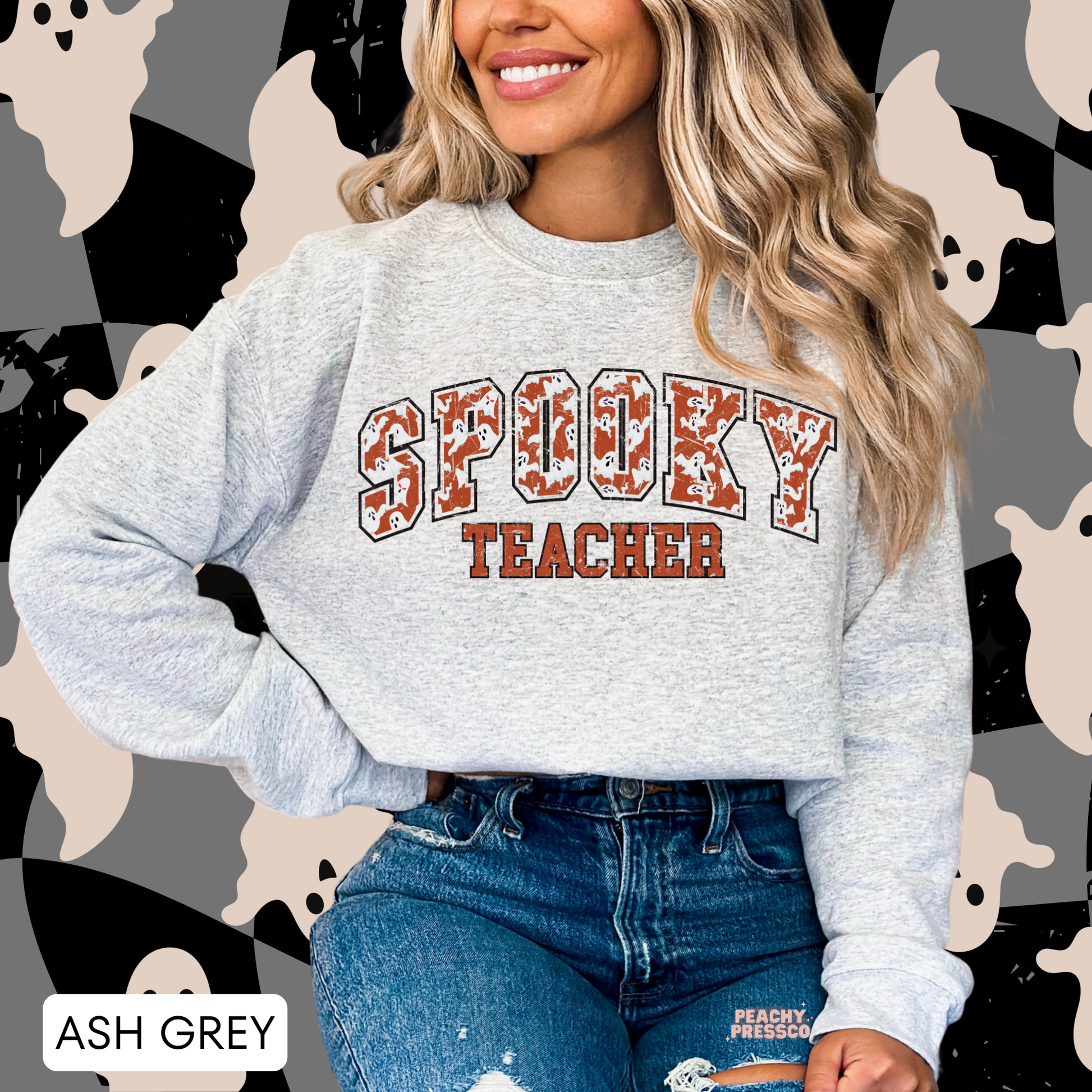 Woman wearing an ash grey Spooky Teacher Halloween crewneck sweatshirt featuring distressed varsity ghost lettering.