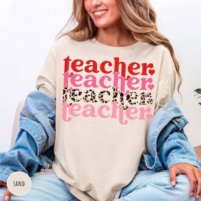 Sand shirt featuring a stacked Valentine teacher typography design with layered pink lettering and leopard print for Valentine's Day.