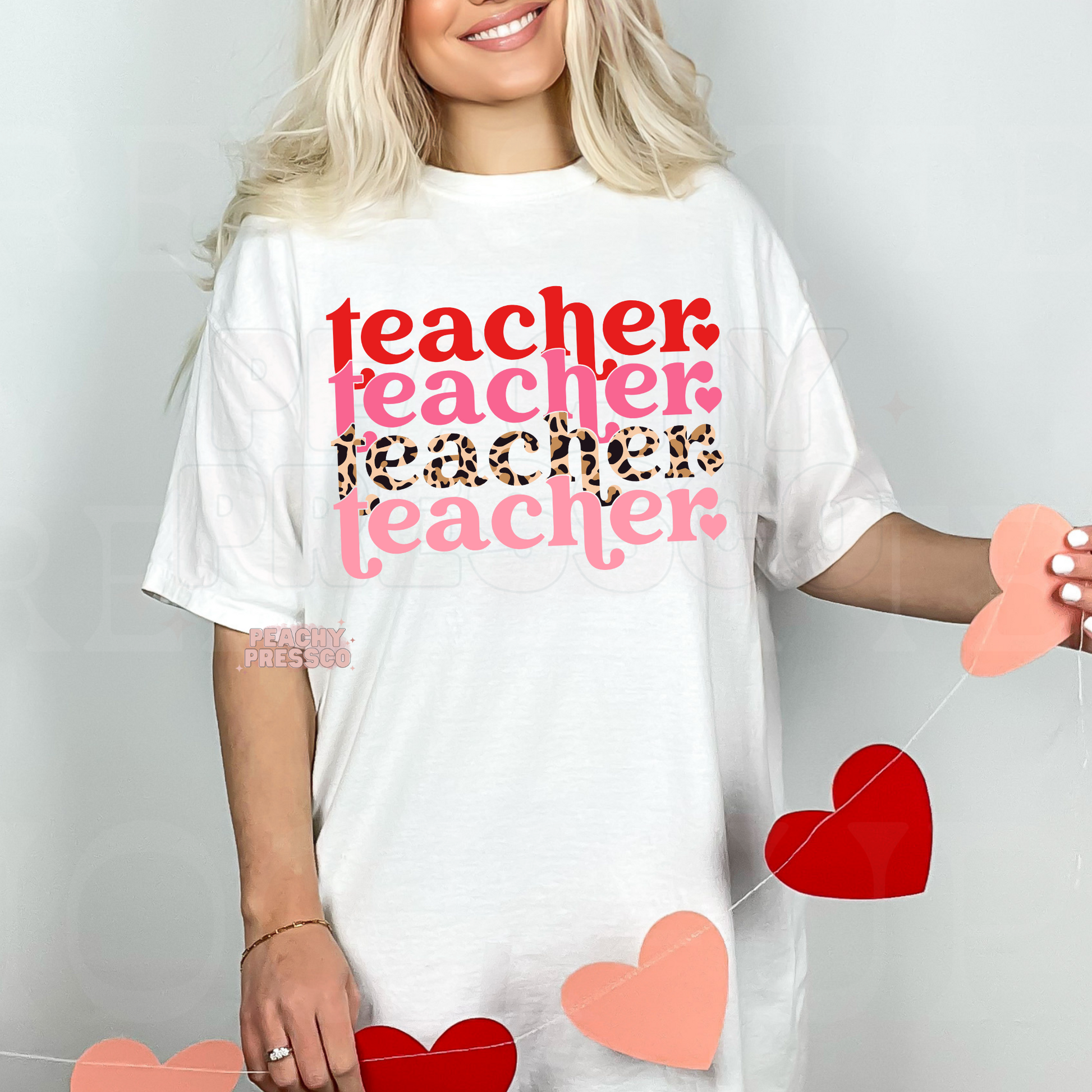 White unisex t-shirt featuring a stacked Valentine teacher typography graphic with layered pink text and leopard print design.