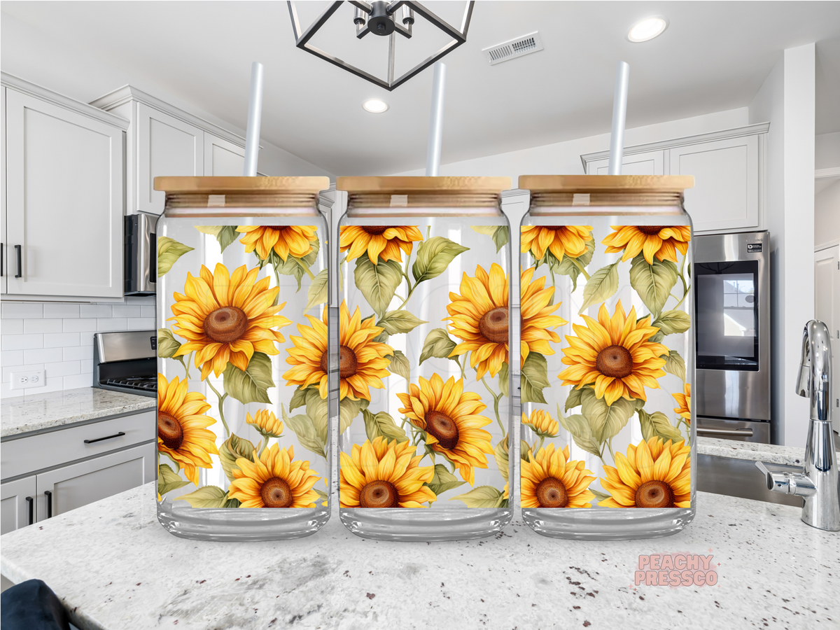 16 oz clear glass cup featuring a seamless sunflower pattern with bright yellow blooms and green leaves. Includes bamboo lid and reusable straw.