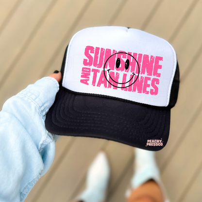Black and white foam trucker hat with a vibrant pink "Sunshine and Tan Lines" design and smiley face graphic. Cute unisex summer hat for beach vacations, pool days, concerts, and everyday wear.