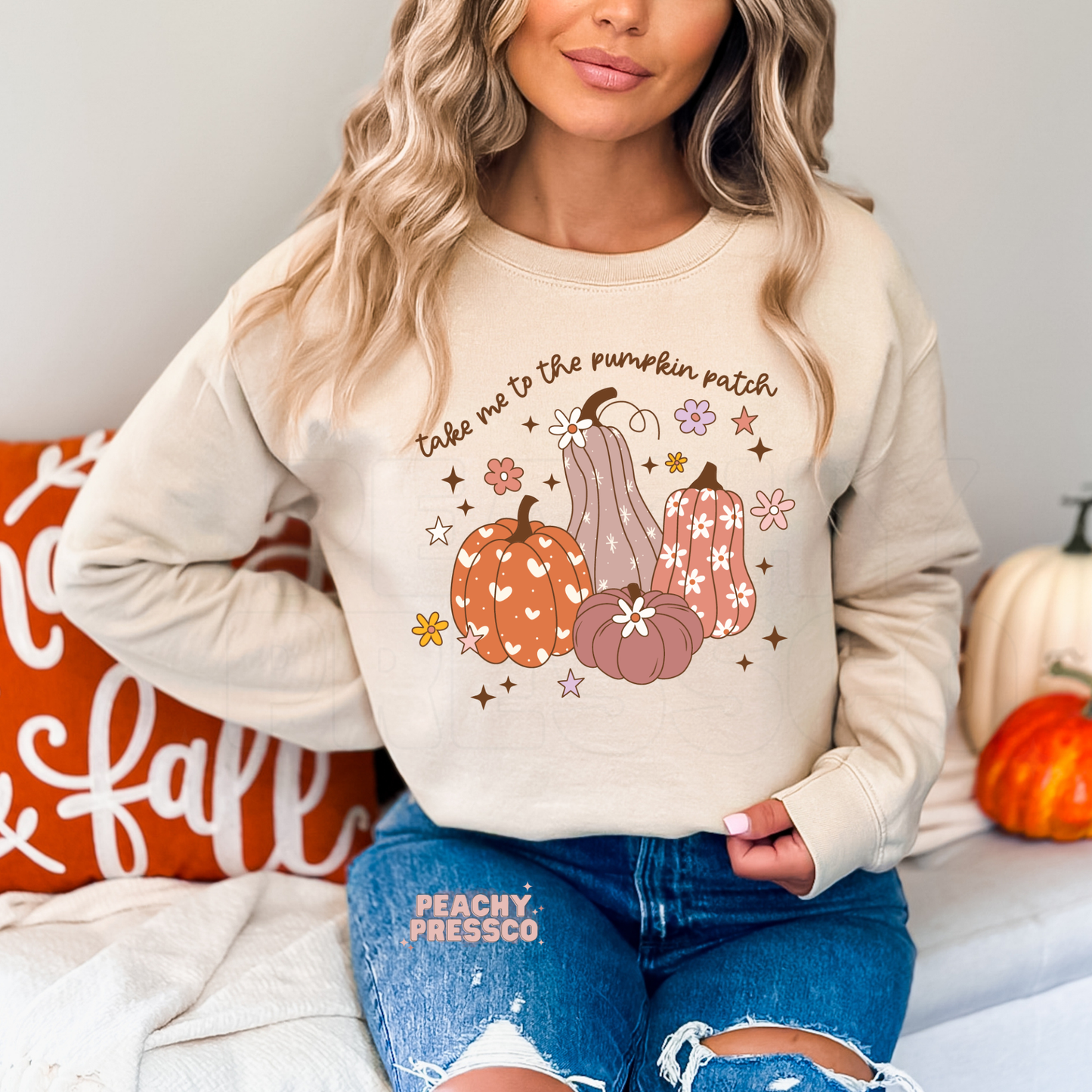 Woman wearing a sand crewneck sweatshirt featuring a cute "Take Me To The Pumpkin Patch" graphic with decorative pumpkins, flowers, and stars, perfect for pumpkin patch visits, fall festivals, and cozy autumn outfits.