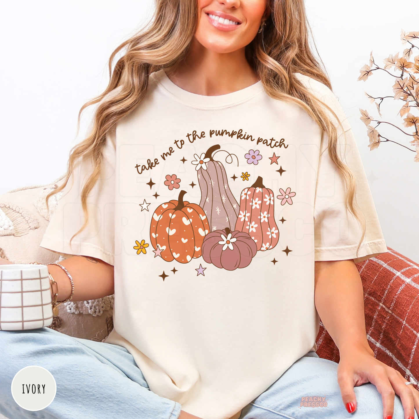 Woman wearing an ivory graphic t-shirt featuring a "Take Me To The Pumpkin Patch" fall design with floral pumpkins and autumn accents, perfect for pumpkin patch trips, hayrides, and cozy fall days.