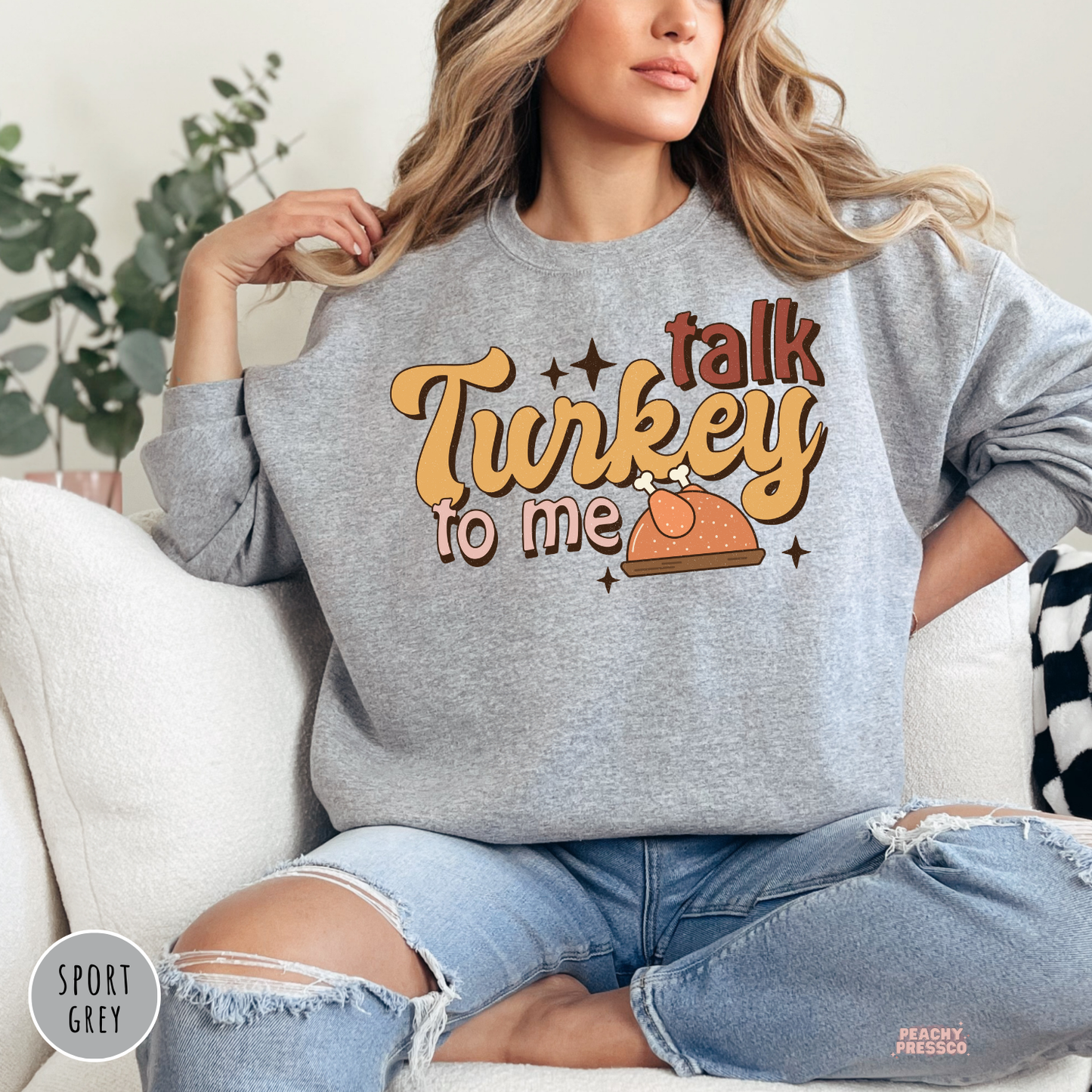 Woman wearing a sport grey crewneck sweatshirt with a retro "Talk Turkey To Me" Thanksgiving graphic featuring a turkey illustration, a cozy fall sweatshirt for Thanksgiving, Friendsgiving, and seasonal celebrations.