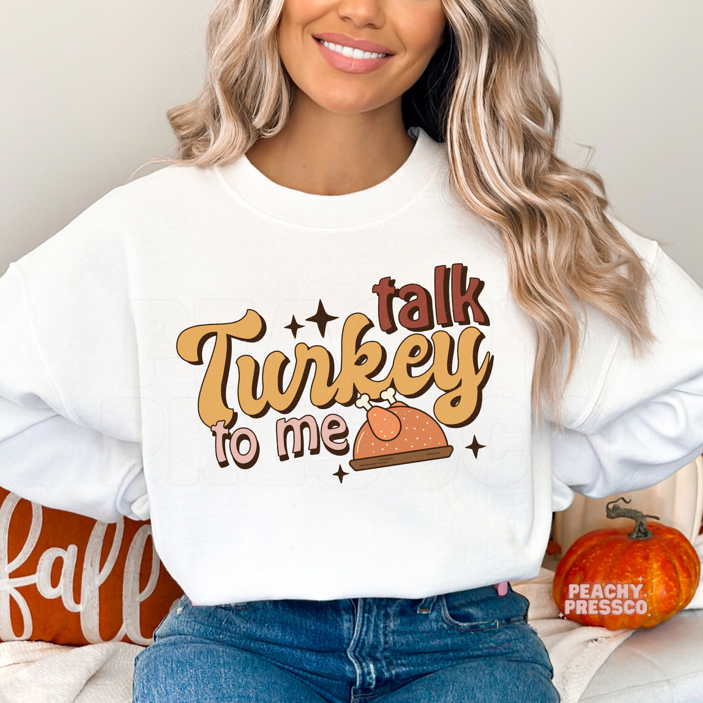 Woman wearing a white crewneck sweatshirt featuring a retro "Talk Turkey To Me" Thanksgiving design with a turkey illustration, a funny and cozy fall sweatshirt for Thanksgiving and Friendsgiving.
