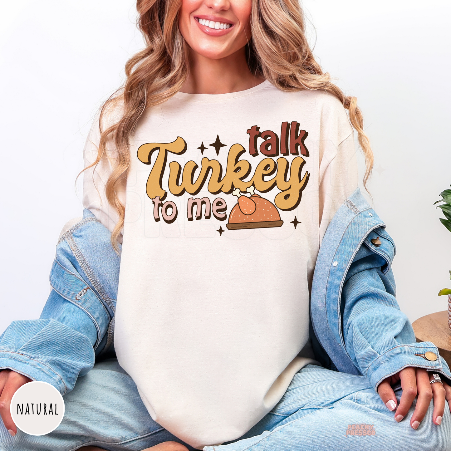 Woman wearing a natural shirt featuring a retro "Talk Turkey To Me" Thanksgiving design with a roasted turkey graphic, a stylish autumn sweatshirt for Thanksgiving dinners and fall outings.