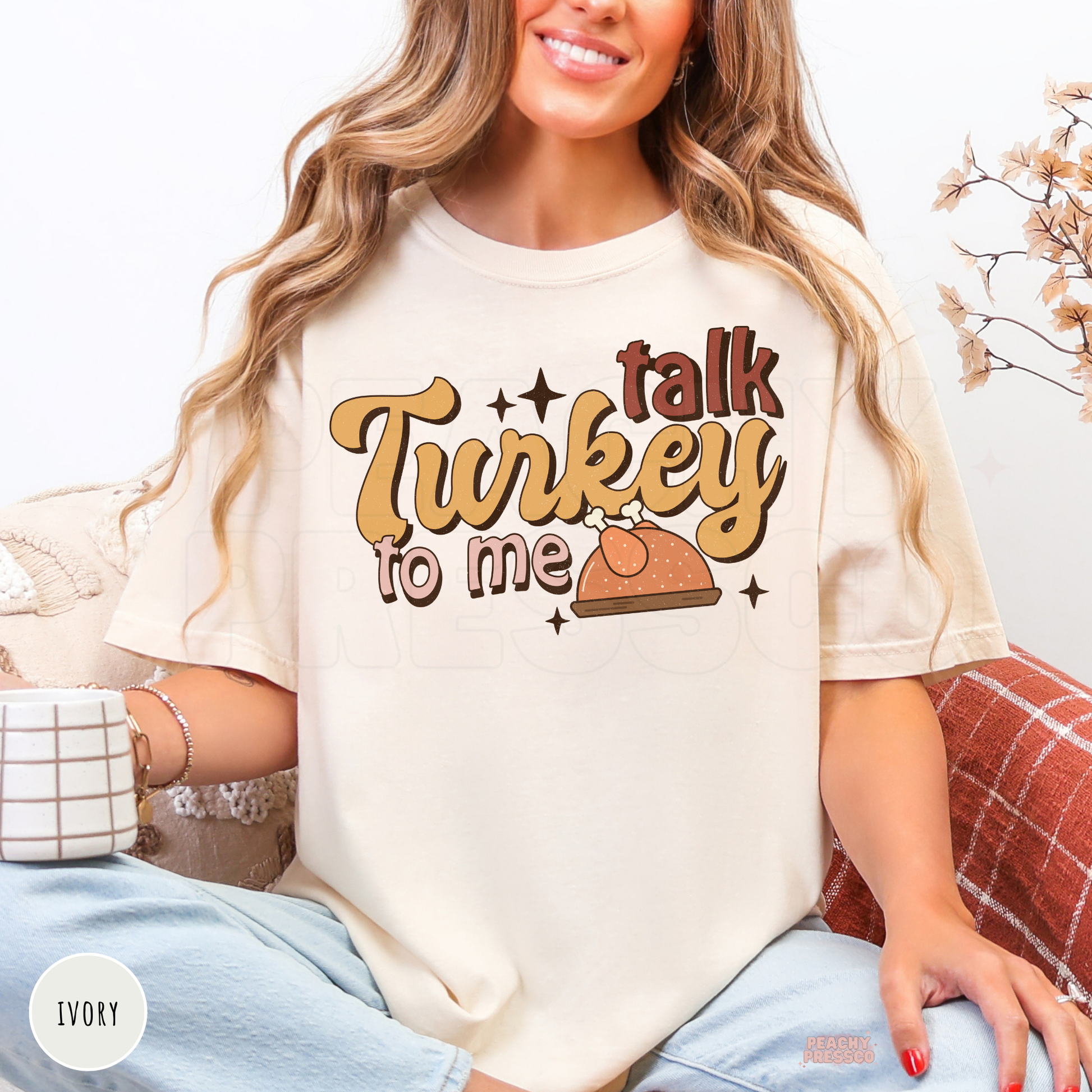 Woman wearing an ivory graphic t-shirt featuring a retro "Talk Turkey To Me" Thanksgiving design with a turkey illustration, a cute and funny fall tee for Thanksgiving dinners, pumpkin patch visits, and autumn festivities.
