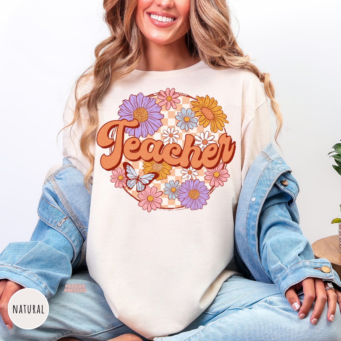 Natural teacher shirt featuring vintage floral "Teacher" lettering with colorful flowers, butterfly, and peach checkerboard design.
