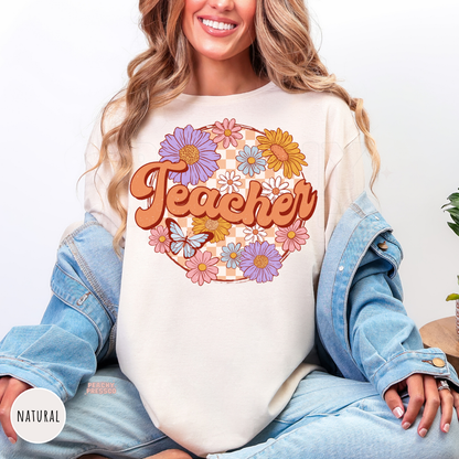 Natural teacher shirt featuring vintage floral "Teacher" lettering with colorful flowers, butterfly, and peach checkerboard design.
