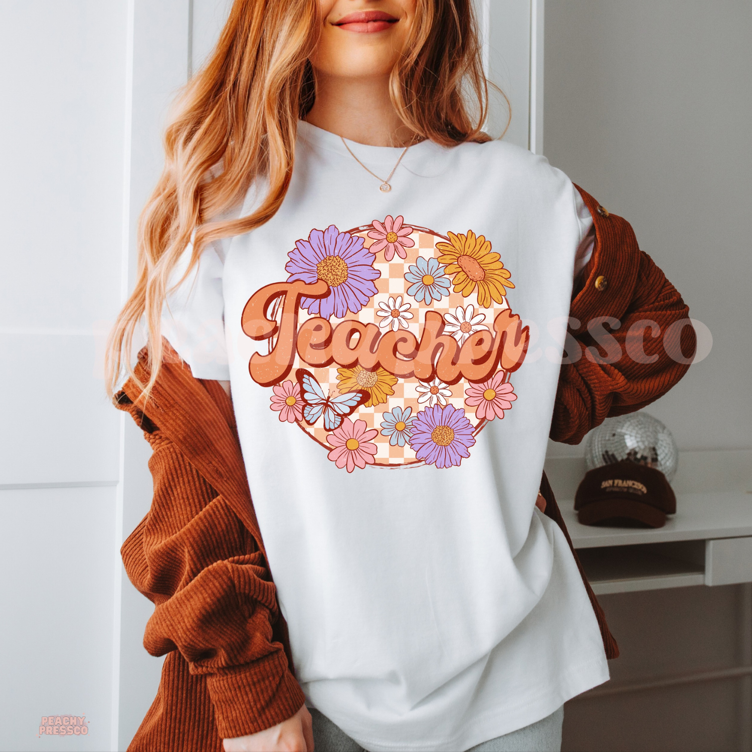 White teacher t-shirt featuring vintage floral "Teacher" design with pastel flowers, butterfly, and peach checkerboard background.