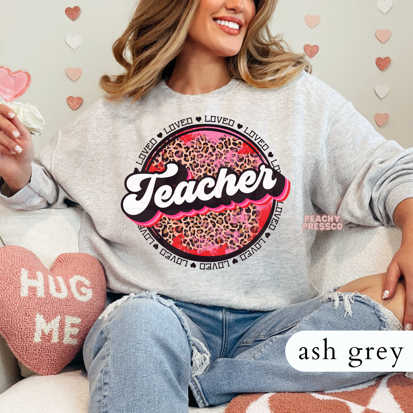 Ash grey crewneck sweatshirt displaying a bold retro Teacher design with pink leopard print and Valentine's-themed loved circle graphic.