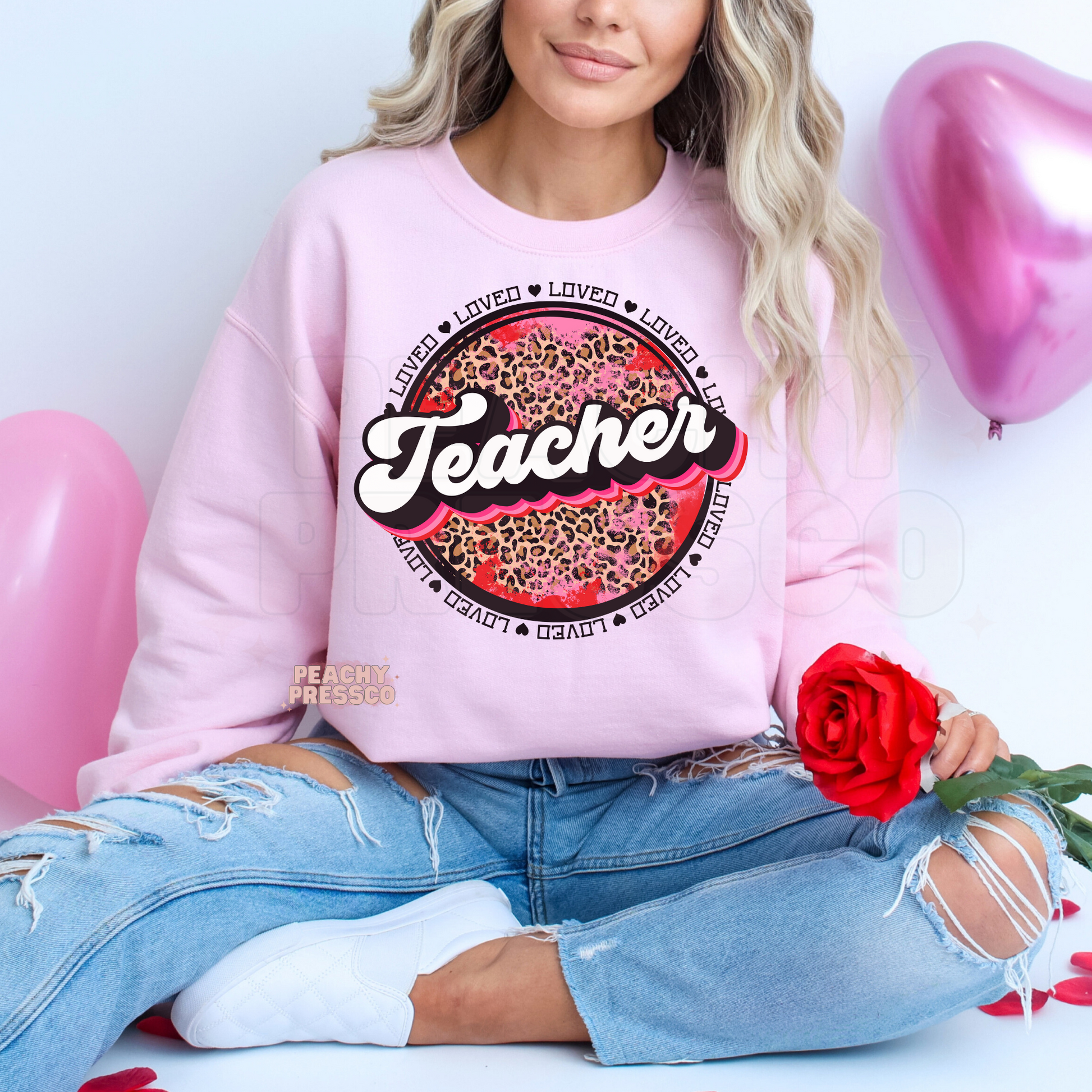 Light pink crewneck sweatshirt featuring a retro Teacher graphic with pink leopard print and heart-themed Valentine's details.