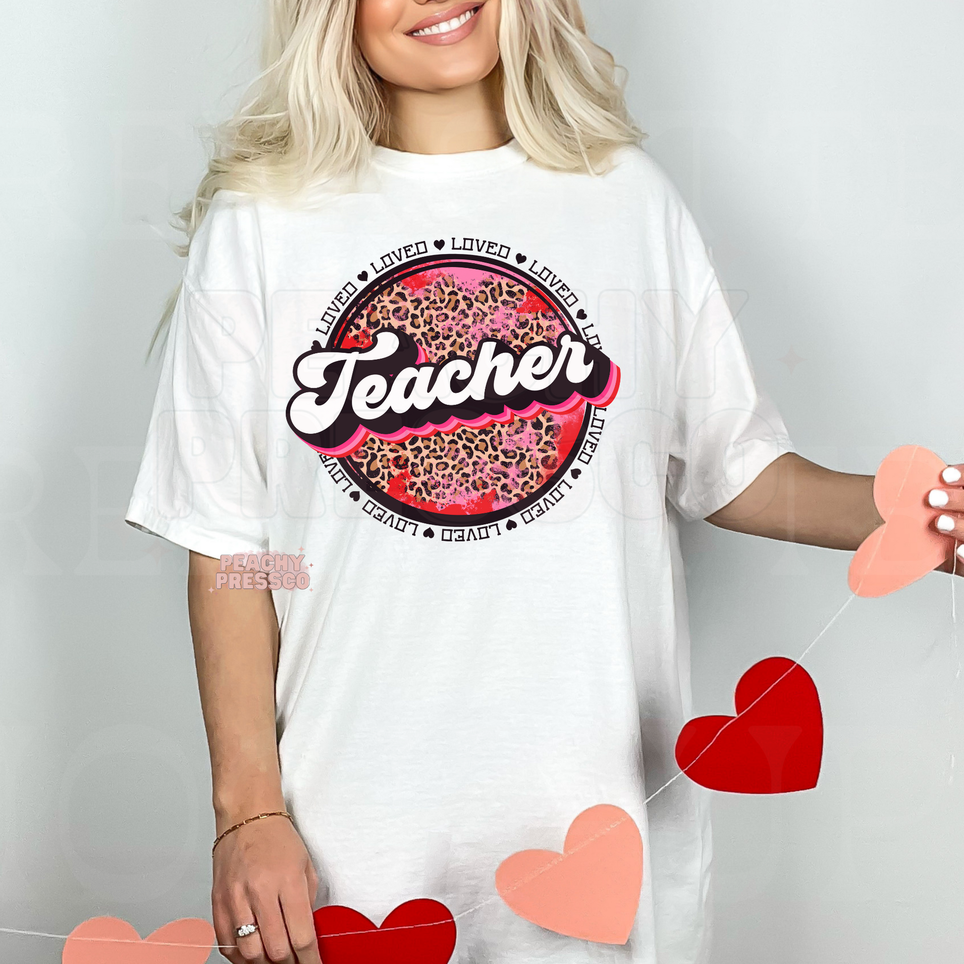 White unisex t-shirt featuring a retro Teacher graphic with vibrant pink leopard print and Valentine's-inspired loved circle design.