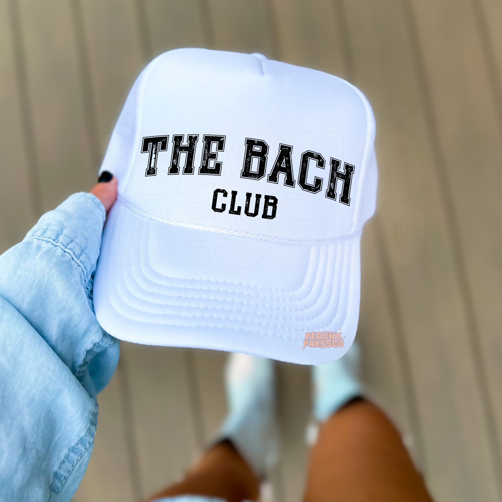 White foam trucker hat featuring "The Bach Club" distressed varsity lettering, perfect for bachelorette parties, bridal trips, and girls' weekends.