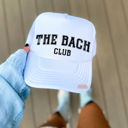 White foam trucker hat featuring "The Bach Club" distressed varsity lettering, perfect for bachelorette parties, bridal trips, and girls' weekends.