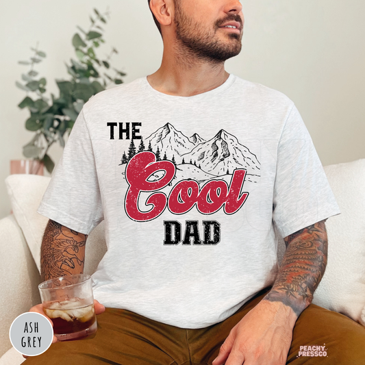 Ash Grey unisex t-shirt featuring The Cool Dad graphic with vintage mountain artwork and distressed red lettering, perfect for Father's Day.