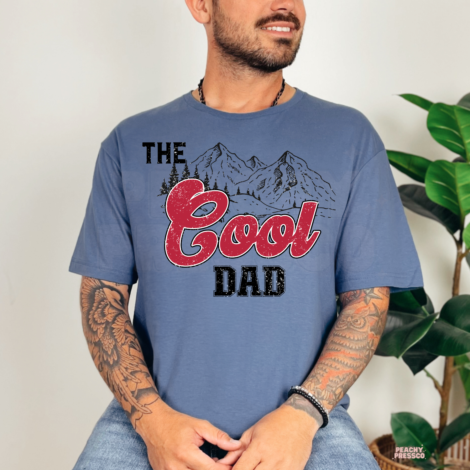 Indigo Blue t-shirt featuring The Cool Dad graphic with vintage red lettering and mountain landscape, a relaxed Father's Day shirt for dads.