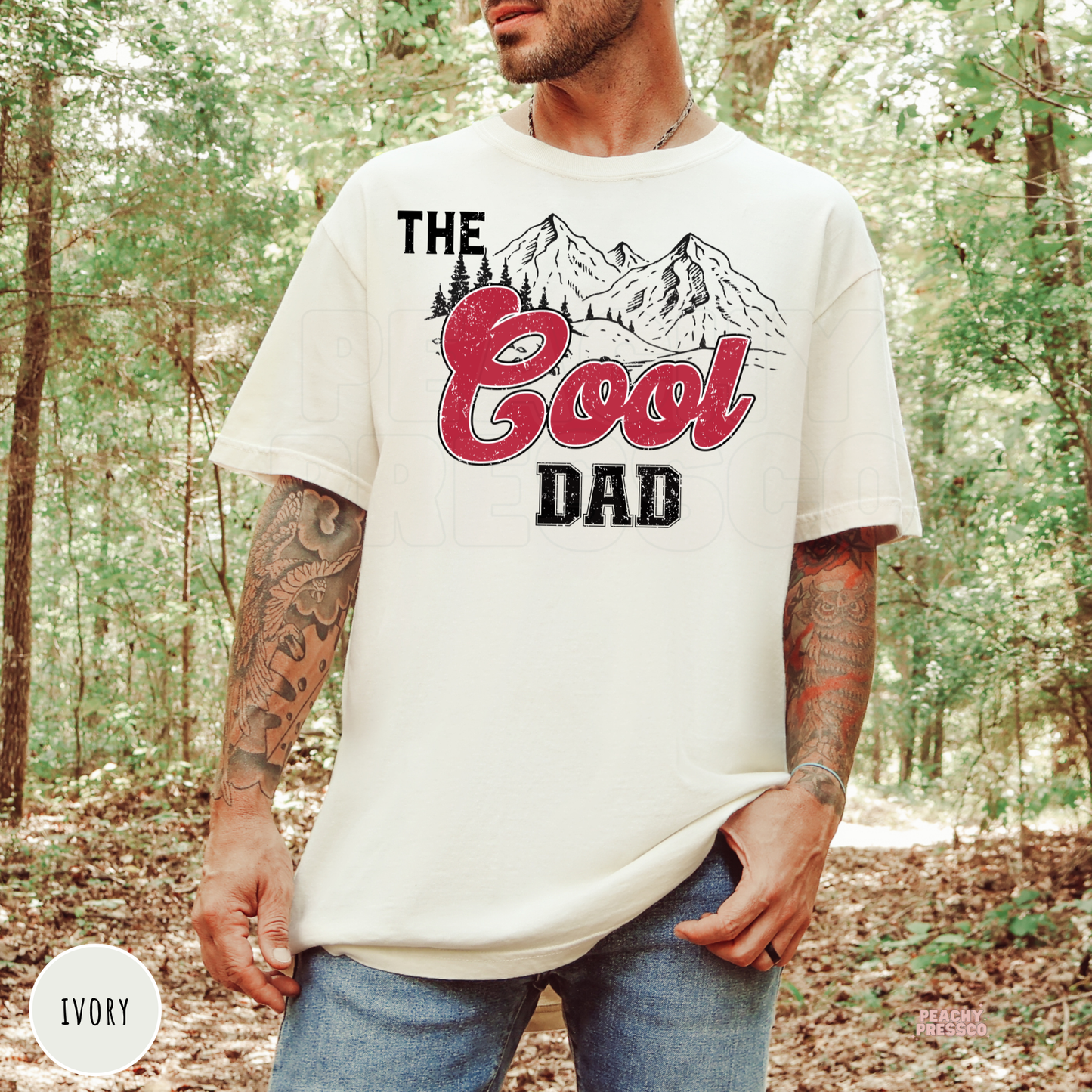 Ivory Comfort Colors t-shirt featuring The Cool Dad graphic with vintage mountain illustration and distressed red lettering, a Father's Day gift for outdoor dads.