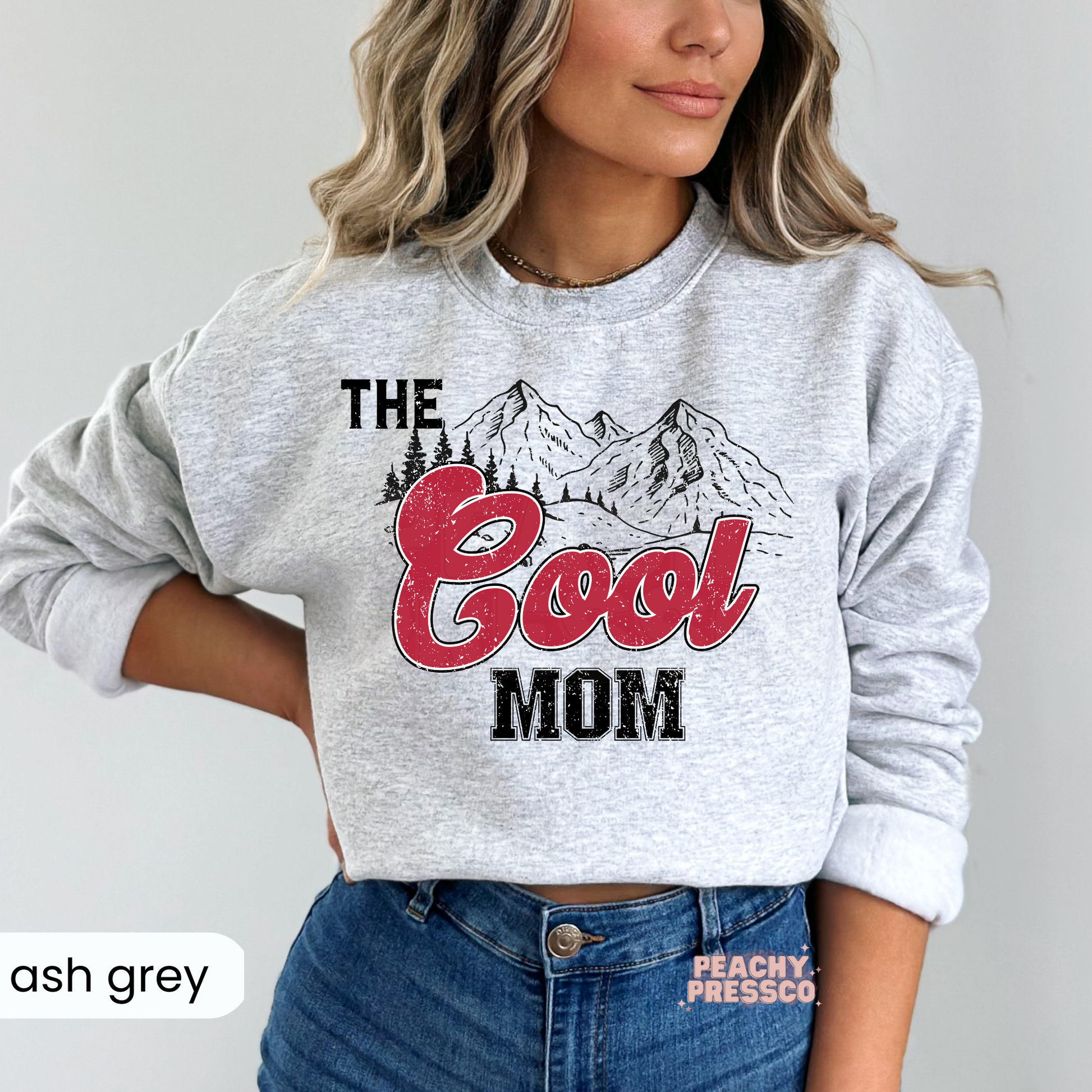 Ash Grey sweatshirt featuring a vintage "The Cool Mom" mountain design with distressed red lettering. Comfortable western-style mom sweatshirt for casual wear.