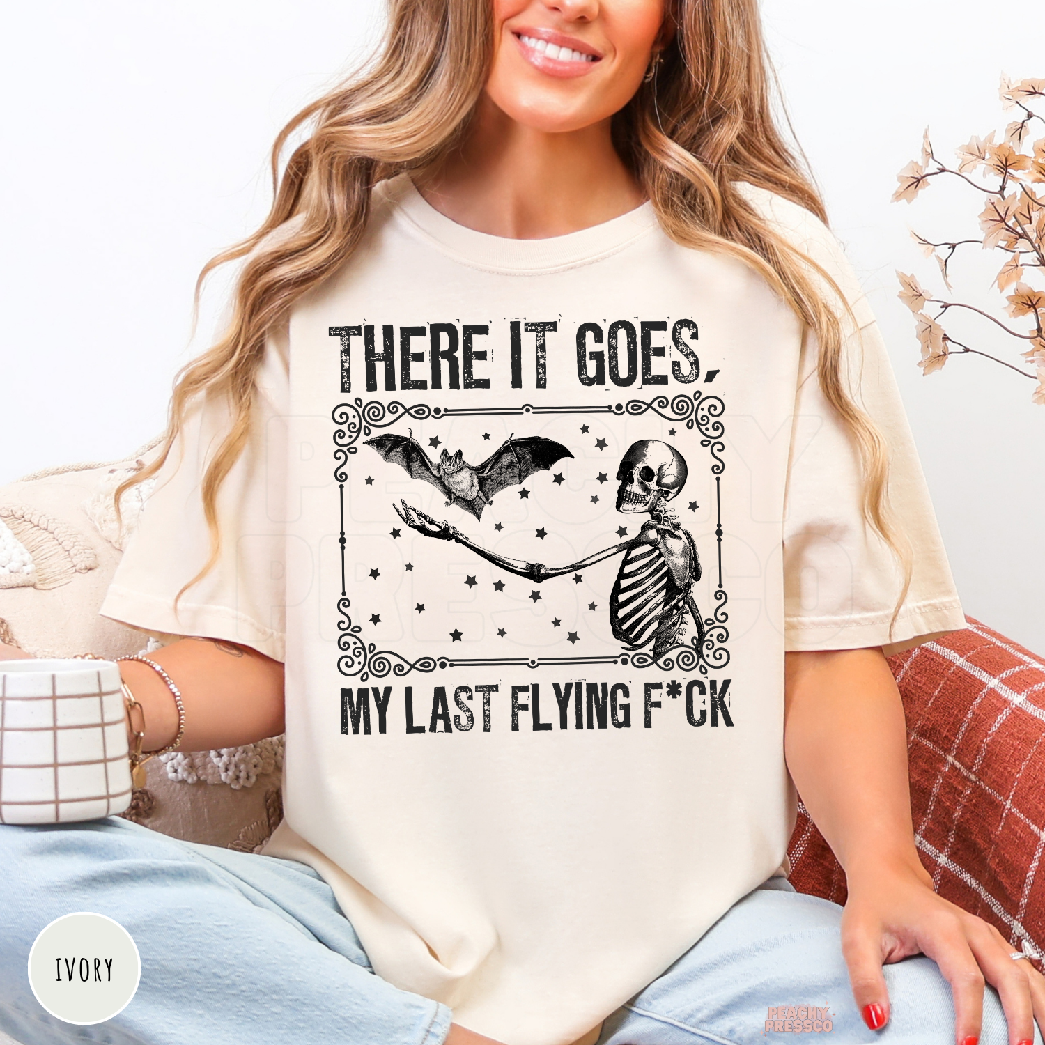 Ivory There It Goes Halloween shirt featuring a vintage skeleton holding a flying bat with spooky star details