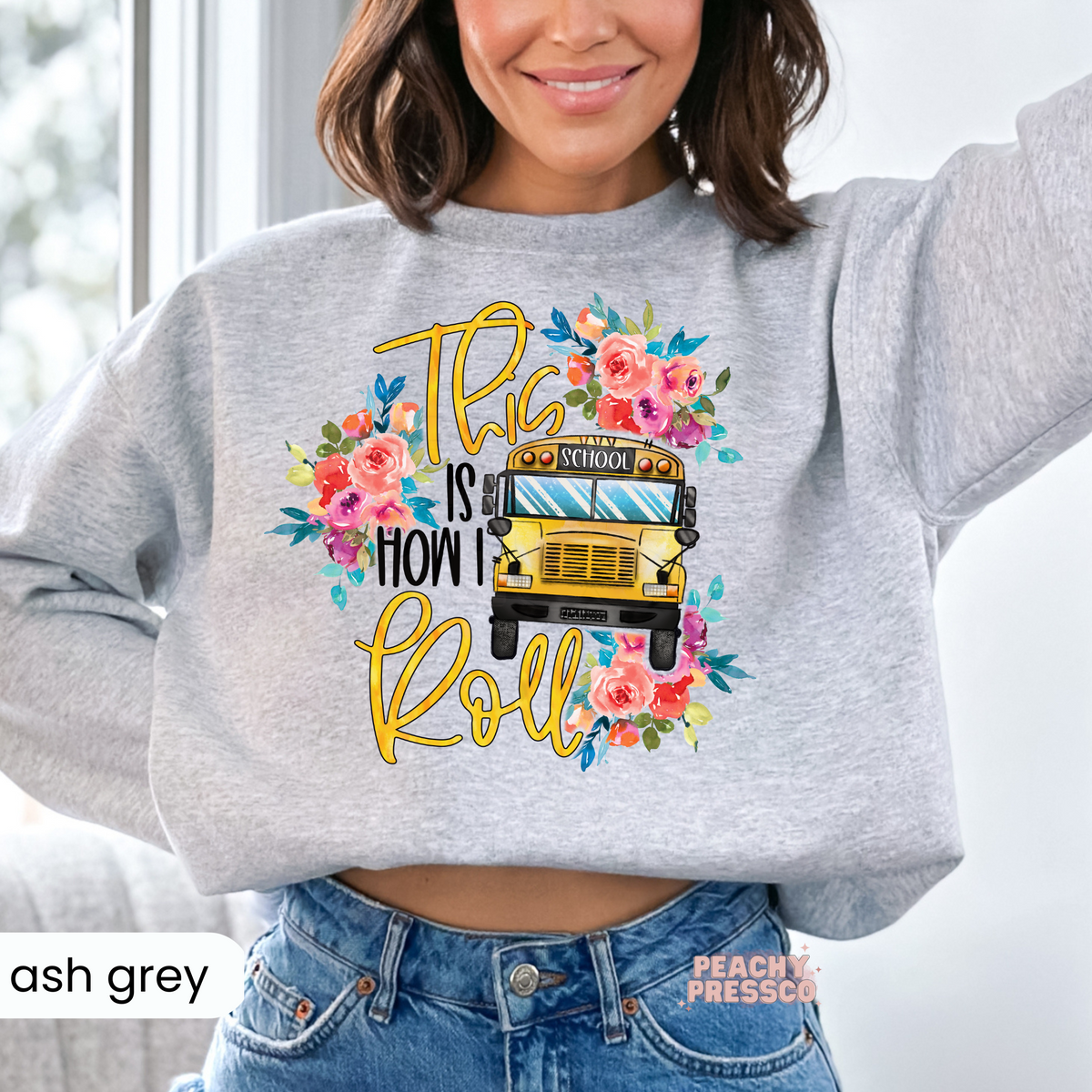 Ash grey teacher sweatshirt featuring a floral school bus graphic with "This Is How I Roll" lettering for teachers and school staff.