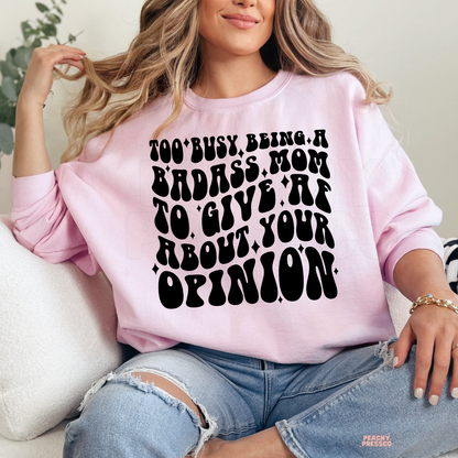 Light pink sweatshirt featuring the bold "Too Busy Being a Badass Mom to Give AF About Your Opinion" graphic. Funny sarcastic mom sweatshirt perfect for busy moms, Mother's Day, and everyday wear.
