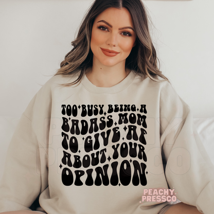 Sand crewneck sweatshirt featuring the "Too Busy Being a Badass Mom to Give AF About Your Opinion" retro statement graphic. Cozy gift for strong, confident moms.