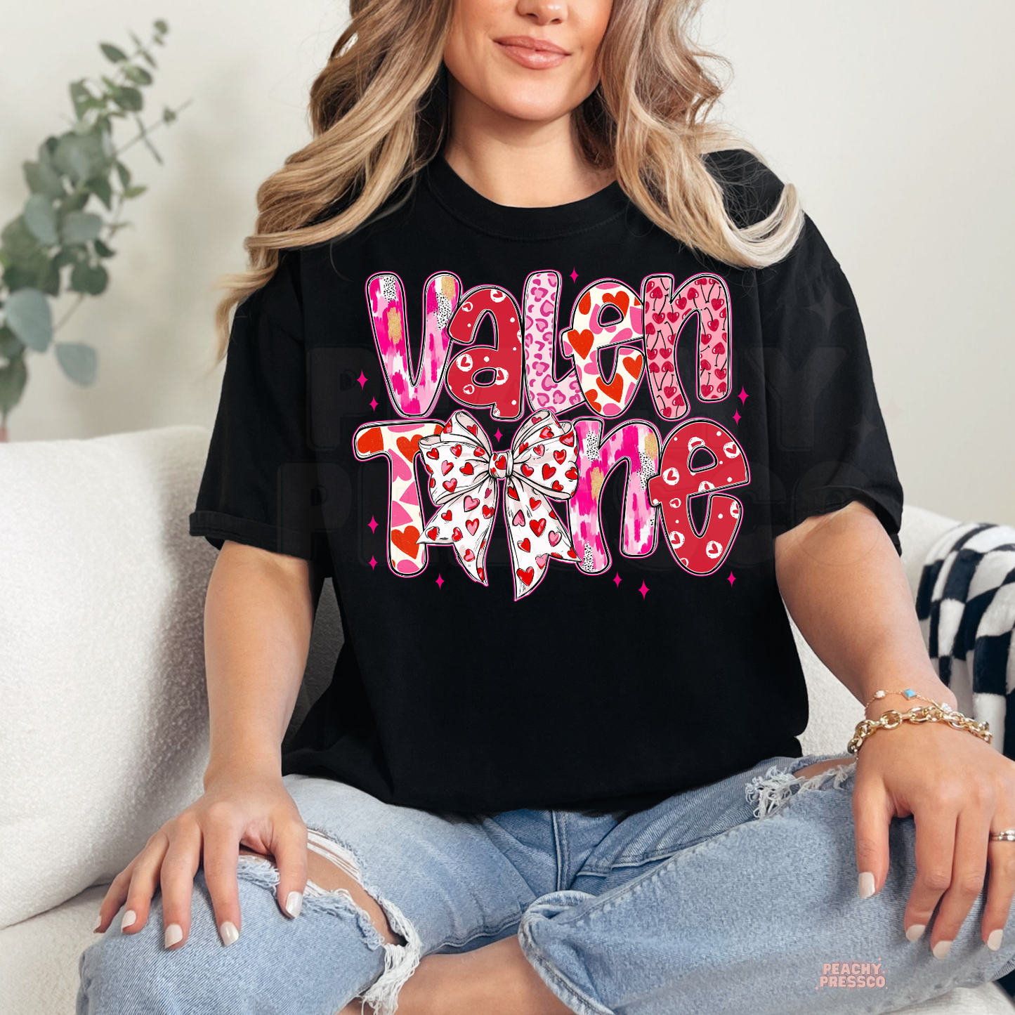 Black unisex t-shirt featuring a vibrant stacked "Valentine" graphic with heart details and a trendy coquette bow.
