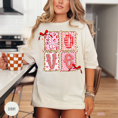 Ivory t-shirt featuring a whimsical LOVE patchwork graphic with pink patterned letters, ribbon bows, and romantic Valentine's accents.