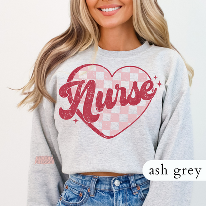 Ash grey crewneck sweatshirt featuring a distressed Nurse graphic with a pink gingham heart for Valentine's Day and everyday wear.