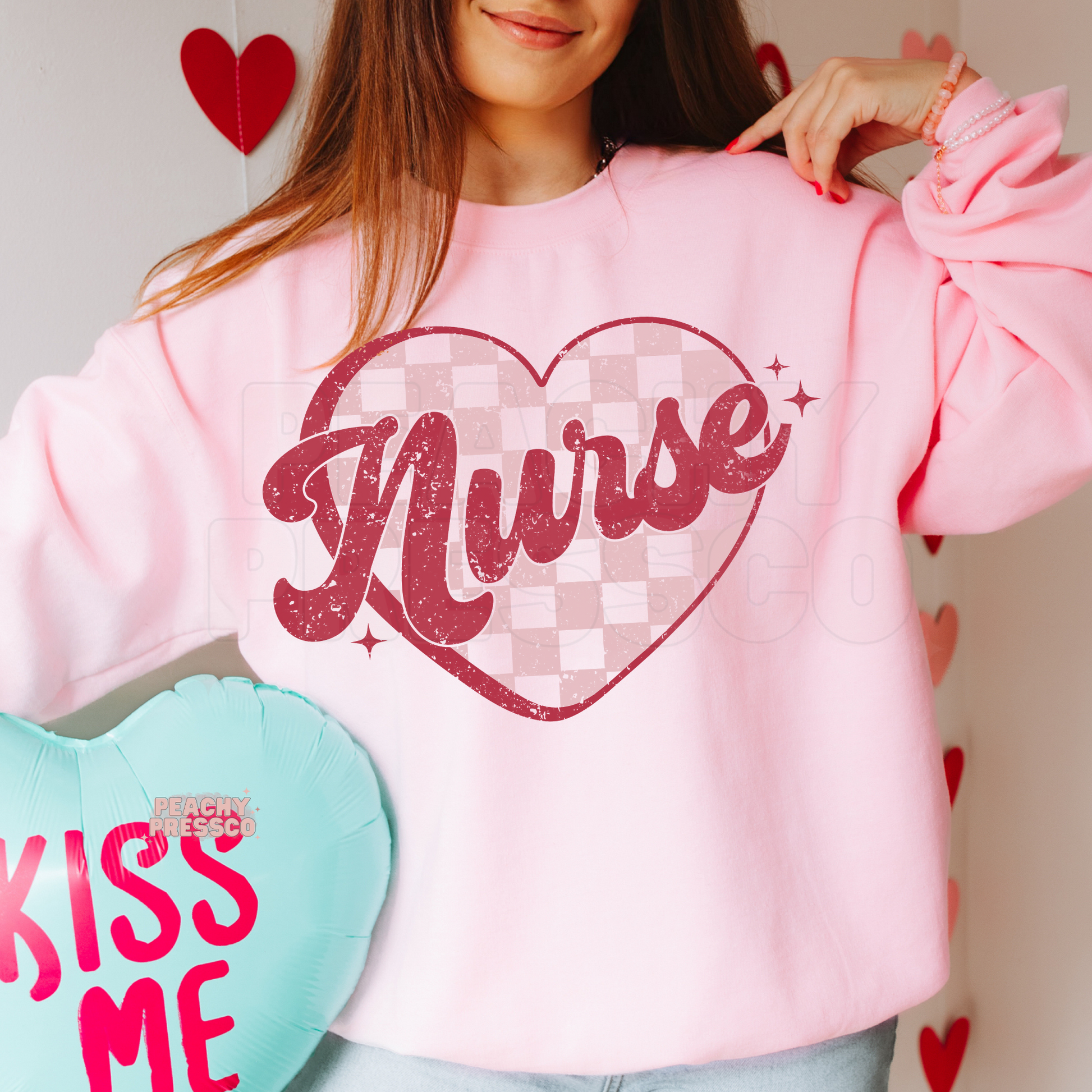 Light pink crewneck sweatshirt featuring a retro Nurse design with a distressed pink script and checkered heart graphic.