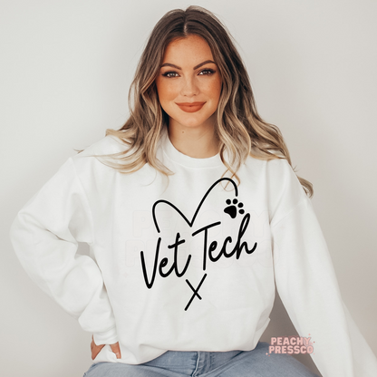 Woman wearing a white sweatshirt featuring a black Vet Tech heart design with a paw print, perfect for veterinary technicians, vet assistants, and animal lovers.