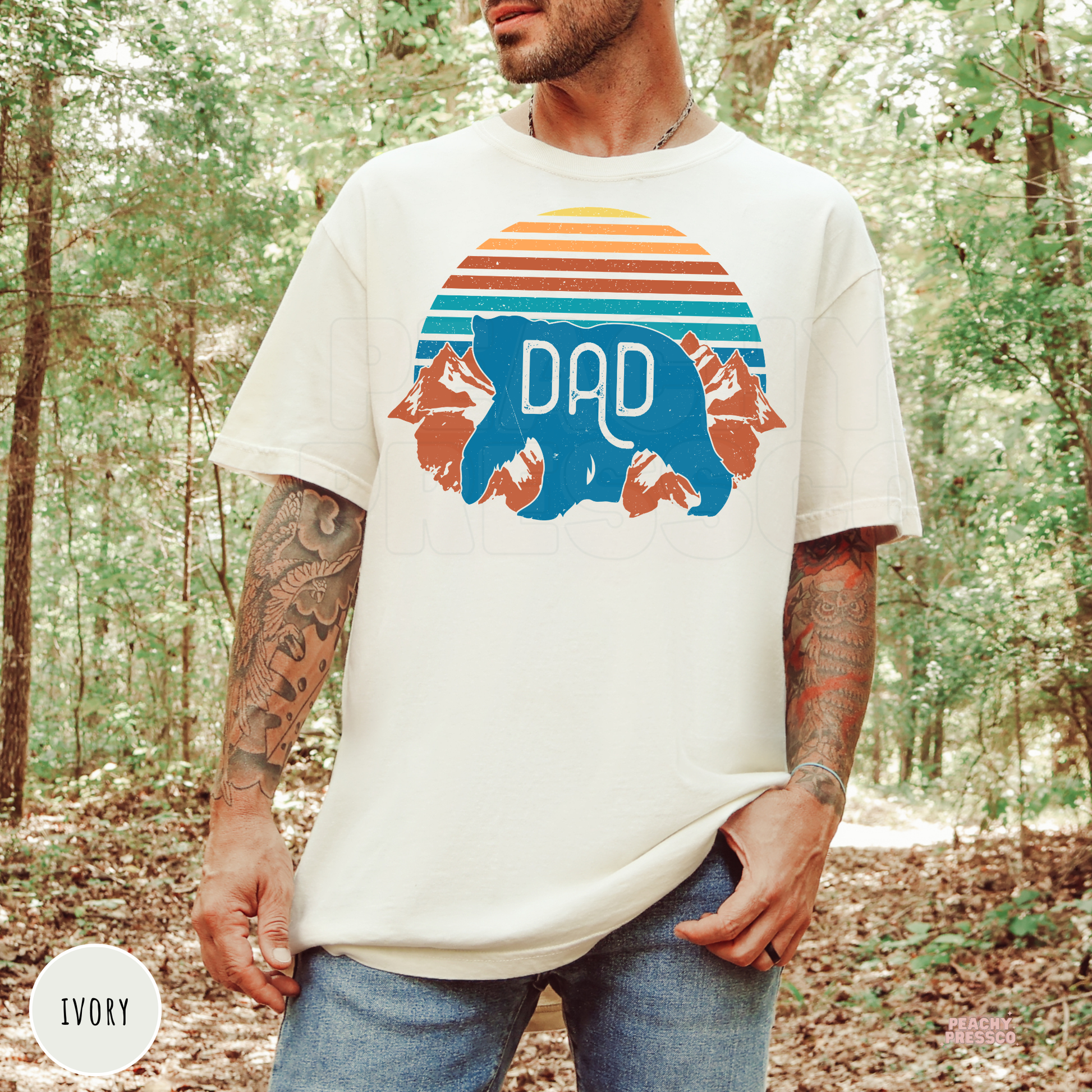 Ivory Comfort Colors t-shirt featuring a vintage sunset, mountain landscape, and blue Dad bear silhouette, an outdoors-inspired Father's Day gift.