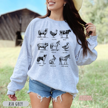 Woman modeling an ash grey sweatshirt with a black and white vintage farm animal sounds illustration and farmhouse-inspired design.