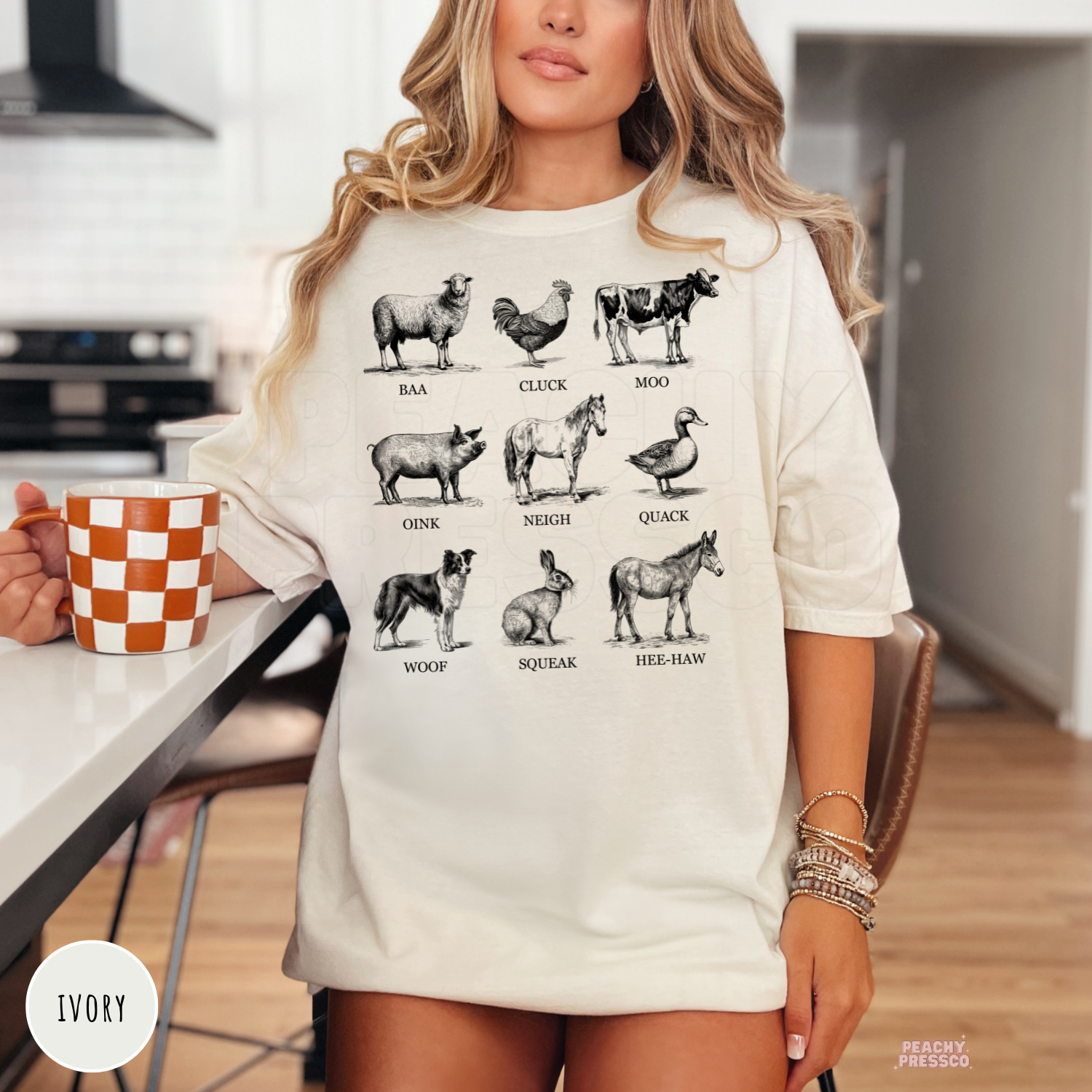 Woman wearing an ivory t-shirt featuring vintage farm animals and their sounds including baa, moo, cluck, oink, neigh, quack, woof, squeak, and hee-haw.