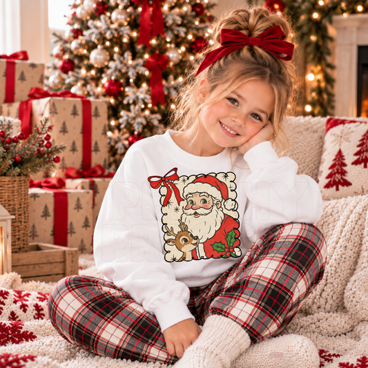 Girl wearing a white kids Christmas crewneck featuring a vintage Santa and reindeer design with red bow