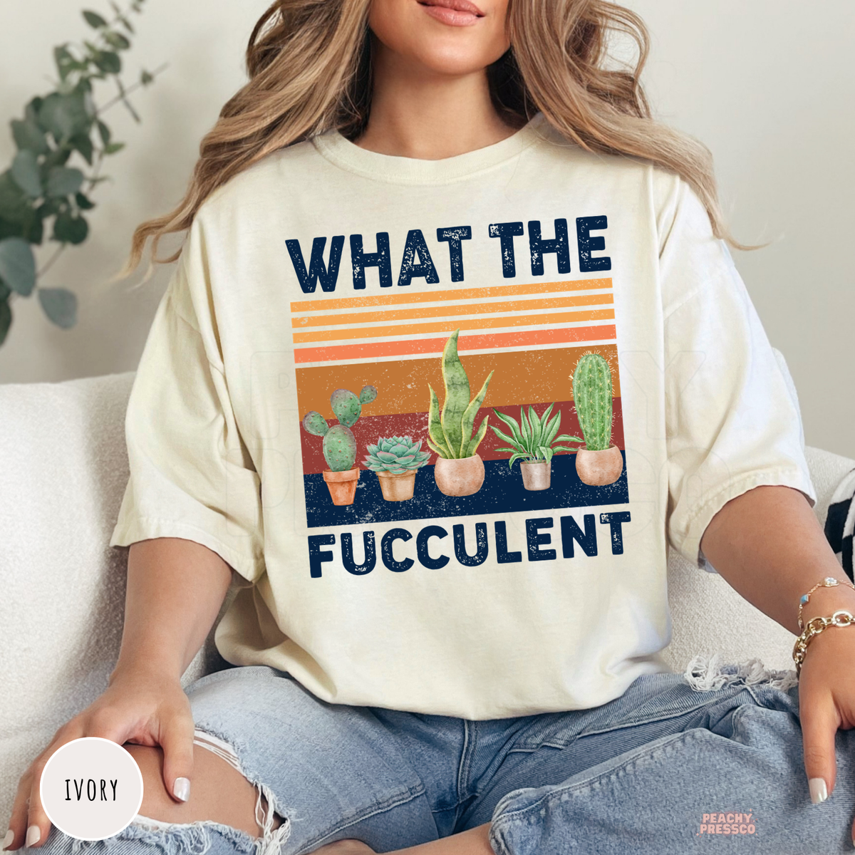 Ivory unisex t-shirt featuring a funny "What the Fucculent" graphic with cactus, succulent, snake plant, and retro sunset stripes. A playful botanical shirt for succulent collectors and indoor plant lovers.