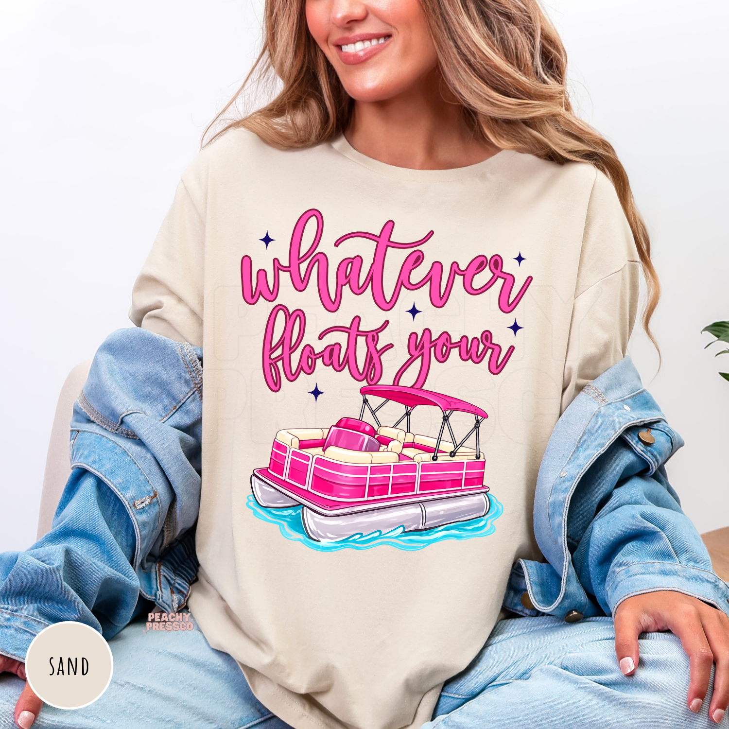 Sand crewneck sweatshirt featuring a bright pink pontoon boat with the phrase "Whatever Floats Your Boat." Cozy lake-inspired sweatshirt perfect for pontoon owners and summer evenings by the water.